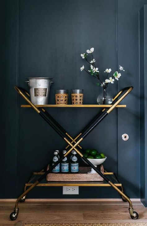 A chic gold and black bar cart is accented with a woven tray and sits in front of a black wall. Office Bar Cart, Styled Bar Cart, Nightstand With Lamp, Katie Davis Design, Black Bar Cart, Acrylic Bar Cart, Modern Farmhouse Office, Katie Davis, Blue Velvet Couch