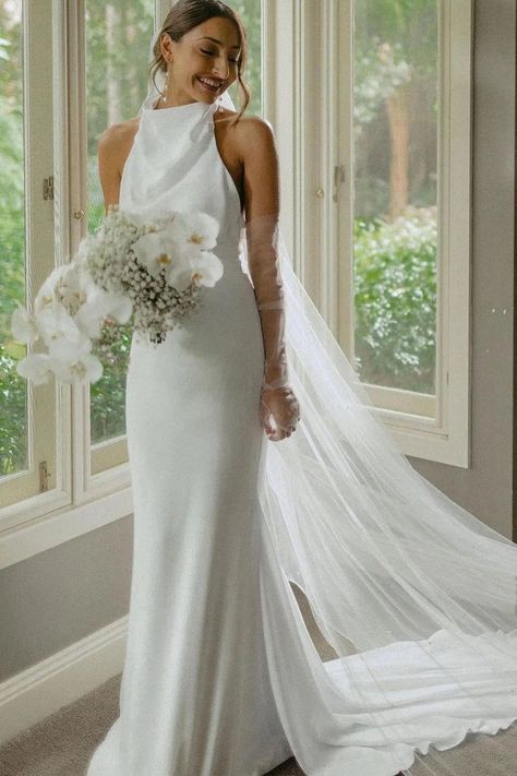 "Hessie" is a combination of elegance and allure. This stunning mermaid-style wedding dress is made from luxurious satin fabric, showing the bride in timeless sophistication. The white color radiates purity and grace, enhancing the bride's natural beauty. Featuring a sweeping train for added drama, "Hessie" showcases a Wedding Dresses Simple High Neck, Waterfront Wedding Dress, Silky Halter Wedding Dress, Timeless Wedding Reception Dress, Halter Wedding Dress With Sleeves, High Neck Wedding Dress With Veil, White Silk Halter Wedding Dress, Fitted Classic Wedding Dress, Halter Neck Satin Wedding Dress