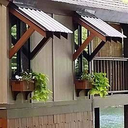 brown window boxes on lake house with bahama style window roof Window Pergolas, Rooftop Planters, Winter Window Boxes, Fall Window Boxes, House Awnings, Corner Trim, Balcony Planters, Porch Planters, Lake Home