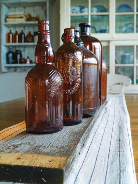 Amber glass bottles lined up on a shelf Amber Wedding Decor, Glass Bottle Decor, Brown Glass Bottles, Farmhouse Inspiration, Amber Glass Jars, Amber Bottles, Amber Glass Bottles, Medicine Bottles, Seasonal Flowers