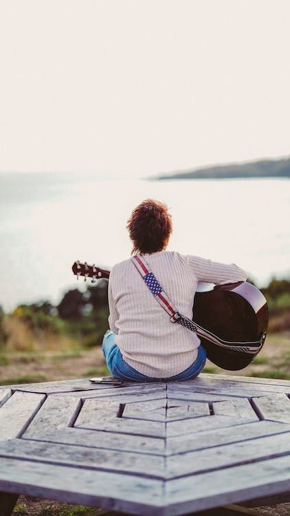 A Back View of a Person Sitting while Playing Guitar · Free Stock Photo A Person Sitting, Guitar Posters, White Long Sleeves, Board Inspiration, Person Sitting, Back View, Birds Eye View, Sit Back, Birds Eye