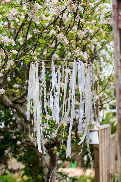 Ribbon and pearl chandelier hanging in tree. Ribbon Hanging From Trees, Whimsical Backdrop, Ribbon Chandelier, Deco Champetre, Decoration Evenementielle, Pearl Chandelier, Celebrate Good Times, Boho Party, Hanging Chandelier