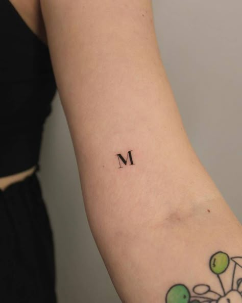 Tattoo of the letter "M" located on the bicep. Small M Initial Tattoo, M H Tattoo Letter, M M Tattoo Letter, Small Letter M Tattoo, M Squared Tattoo, Red M Tattoo, Letter M Tattoo Ideas Initials, M Tattoos Letter, The Letter M Tattoo