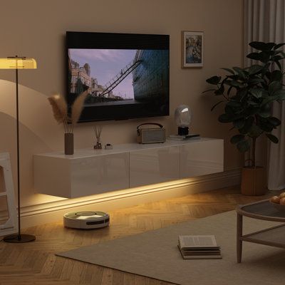 The suspended wall-mounted TV cabinet can adjust the installation height according to your own preferences and needs, saving space and making it very convenient for your sweeping robot to enter and exit for cleaning. The bottom of the TV cabinet is equipped with LED lights, with 44 different colors of lights to choose from. You can use the mobile app or use the remote control to adjust the light color. Color: White | Ivy Bronx Damitra Floating TV Stand for TVs up to 75" Wood in White, Size 9.8 H Tv Stand Hanging, Tv Stand Lights, Tv Stand Decor Ideas, Floating Tv Cabinet, Wall Mount Tv Stand, Tv Stand With Led Lights, Wall Mounted Tv Cabinet, Hanging Tv, Led Wall Decor