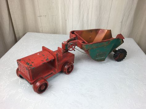 This is a very nice pressed steel toy dump truck/tractor marked as  a 'STRUCTO ROCKER' on the labels.  Overall, this rocker is in good played with condition but missing the engine and stack.  It has 2  labels in reasonable shape, and appears to have been painted  red over what may be the original green color which covers the outside of the dumper.  It has 6 rubber tires in usable condition, all well attached and functional.  All mechanical joints and features in very good condition.  The dumper is operated by a wheel and string which is in working condition.  A pretty cool  example of the ROCKER in a much loved and played with condition. Mechanical Joints, Pressed Steel Toy, Pull Toy, Construction Equipment, Dump Truck, Rubber Tires, Toy Vehicles, Pretty Cool, Vintage 1950s