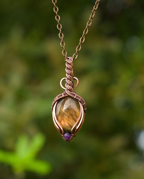 "This gemstone pendant features a flashy orange labradorite oval with a faceted royal purple amethyst accent. The crystal is wire wrapped in pure copper with a triple wire bail that is twisted into a Celtic braid design with minimal coverage on the front of the stone. The wire has been antiqued and hand polished for an antique look. This unisex pendant comes with an 18\" antique copper plated chain and lobster clasp. If you prefer a different length, let me know and I will gladly customize your chain for you. You can upgrade to a pure copper ball chain for $5. It ships for free in US in a gift box. If you are sending this as a gift to someone else, I will happily include a handwritten card with a message from you! Just let me know what you'd like to say." Diy Necklace Designs, Celtic Braid, Wire Wrap Cabochon, Wire Jewelry Rings, Wire Wrap Jewelry Designs, Wire Wrapped Crystal, Wire Wrapped Jewelry Diy, Instruções Origami, Bijoux Fil Aluminium