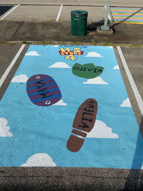 Parking spot painted bright blue background with white clouds from the movie Toy Story. Three footprints, Woody’s, Buzz Lightyear’s, and Rex’s with names “Amelia”, “Maya”, and “Olivia” painted on. “HS Story” in the design of the Toy Story logo. Toy Story Senior Parking Spots, Toy Story Parking Spot Painting, Senior Car Parking Spots, Disney Parking Spot Painting Ideas, Senior Tiles, Senior Year Parking Spot Ideas, Cute Parking Spot Painting Ideas, Senior Diy, Painted Parking Spaces Ideas