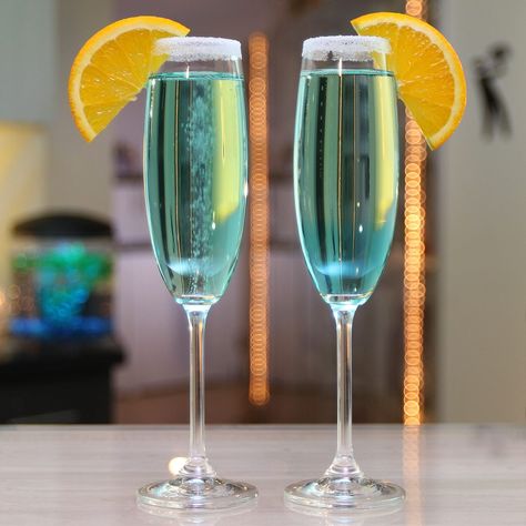 MIDNIGHT KISS 3/4 oz. (22ml) Vodka 5 oz. (180ml) Champagne 1/4 oz. (7ml) Blue Curaçao Rim: Sugar Rim  Garnish: Orange Slice  PREPARATION 1. Rim the edge of your glass using an orange wedge and sugar.  2. Pour in vodka and champagne. 3. Add blue curaçao and garnish with an orange slice.  DRINK RESPONSIBLY! Champagne Mixed Drinks, Cocktail Recipes Vodka, Nye Drinks, Blue Curacao Drinks, Cocktail With Vodka, Kiss Cocktail, Vodka Mixers, Vodka Blue, Champagne Recipes Cocktails