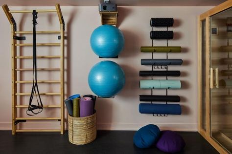 This gym and wellness space stays organized and clutter-free, thanks to savvy storage solutions. That includes a foam mat holder on the wall and a metal hanging organizer that offers easy access to assorted yoga gear. Small Gym Design, Half Garage Gym Ideas, Home Exercise Room, Half Garage Gym, Gym Room Ideas, Gym Design Ideas, Fitness Storage, Garage Gym Ideas, Gym Organizer