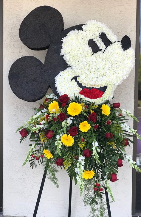 Mickey Mouse using a variety of mums, gerbera daisy, roses, snap dragons, solidago and carnations. #funeral #flowers #funeralflowers #theflowershopfairoaks #mickeymouse #mickeymouseflowers Mickey Mouse Bouquet, Lion King Flower Arrangement, Mickey Mouse Floral Arrangements, Mickey Bouquet, Mickey Mouse Flower Arrangement, Mickey Flower Arrangement, Mickey Mouse Flowers, Minnie Floral Wreath, Minnie Mouse Wreath