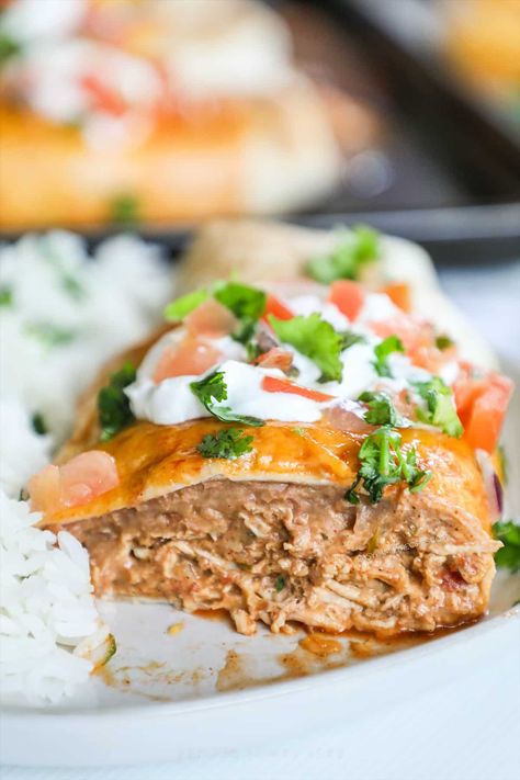 These easy Baked Chicken Chimichangas come together in less than 30 minutes - and with under 10 ingredients! These crispy smothered chicken chimichangas are baked in the oven for a healthier, less-messy version of chimichangas. With shredded chicken, refried beans, cheese, and enchilada sauce, this chicken chimichanga recipe is a family-friendly and super easy dinner! Chicken Chimichanga Recipe, Baked Chicken Chimichangas, Chicken Chimichanga, Chicken Chimichangas, Chimichanga Recipe, Baked Chicken Recipes Easy, Super Easy Dinner, Smothered Chicken, Crispy Baked Chicken