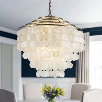 Indulge in the beauty of the ocean with our 6-light glam coastal capiz-tiered chandelier, a stunning harmony of nature and delicacy. This chandelier features four luscious tiers of natural seashells delicately suspended from a frame that glimmers with an antique gold finish, embodying the charm of a starburst bronze frame found in our other cherished designs. Each tier boasts an array of natural seashell accents, as light permeates through the seashell shades, it casts a soft, ambient glow, crea Capiz Chandelier, Capiz Shell Chandelier, Entry Chandelier, Coastal Glam, Shell Chandelier, Cozy Space, Coastal Living, Antique Gold, Hanging Lights