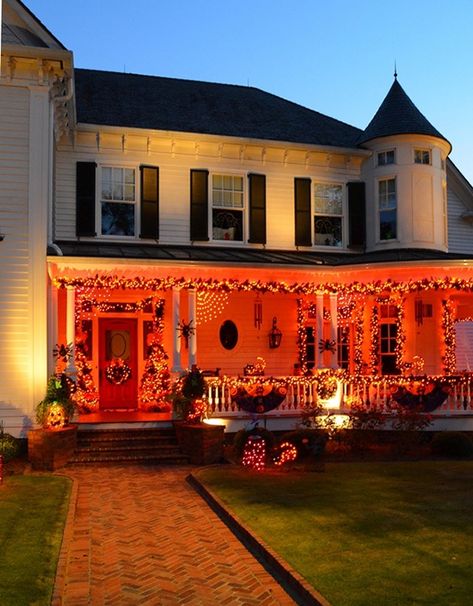 Front Porch Decorated for Halloween with Lights Decorated Halloween Houses, Halloween Wrap Around Porch Decorations, Orange Halloween Lights Outdoor, Halloween House Exterior Decor, Halloween Exterior Lights, Wrap Around Porch Halloween Decor, Halloween House Outside, Halloween Decorated House, Outdoor Halloween Lights