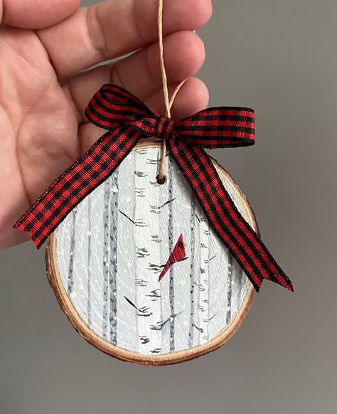 This cheery red cardinal sitting on a branch among birch trees in the snow was hand painted on a live edge slice of pine wood. Perfect for bird and nature lovers to hang on their Christmas tree! Because these are hand painted, no two paintings are exactly alike. The ornament you get may vary slightly from photos.  Dimensions: Vary between 2.75 and 3.5 inches diameter 1/2 inch thick Materials: Live edge pine wood slice Acrylic paint Acrylic varnish Twine Ribbon Shipping: Ready to ship for free wi Sliced Wood Christmas Ornaments, Christmas Tree Wood Slice Ornament, Hand Painted Cardinal Ornaments, Christmas Craft Wood Slice, Painting On Live Edge Wood, Birch Slice Ornaments, Painting Wood Slices Christmas, Fall Wood Slice Ornaments, Wood Slice Ornaments Christmas