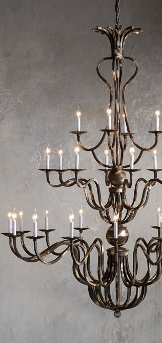 With the ornate detailing and impressive scale of 18th century light fixtures, this chandelier dazzles in a modern home. Its iron frame is brushed with a Dark Silver Clay finish and lends Old World ambiance, while candelabra bulbs catch the light, setting a magical mood over a dining table, living room or grand entry. #chandeliers #lightingfixtures #lighting #rusticlighting #farmhouselighting #decoratingideas #livingrooms #diningrooms #homedecor Entry Chandeliers, Grand Chandelier, Grand Entry, Antler Chandelier, Decorative Wall Sconces, Dining Table Living Room, Silver Clay, Foyer Lighting, Rustic Lamps