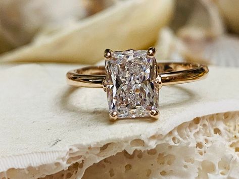 This beautiful 4 prong setting contains a 2.00ct. radiant cut moissanite. The center stone measures 8x6mm.  Color: D (colorless) Clarity: VVS1 This ring is also available in CZ.  The ring is available in sterling silver and 14k white, yellow, or rose gold.  The mounting is a modern, elegant setting with a high polish finish.  This ring comes with a grading certificate.  Please send me a message if you need a size not listed.  This ring can also be customized with any color center stone. All item Engagement Ring Radiant Cut, Engagement Ring Radiant, Radiant Cut Moissanite Engagement Ring, Radiant Cut Engagement Ring, Radiant Diamond Rings, Lab Created Diamond Rings, Oval Solitaire Engagement Ring, Radiant Cut Engagement Rings, Engagement Ring Prices