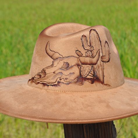 🔥 Saddle up in style with this one-of-a-kind, hand-burned south western fedora! 🤠 Featuring a bold desert design with a skull and cactus 🌵, this hat is perfect for adventurers and trendsetters alike. Every detail is uniquely crafted to stand out in any crowd. Custom hats for those who live wild & free! 🦬 #HandcraftedHats #WesternStyle #DesertVibes #CustomFedora #CowboyFashion #BohoChic #HatArt #BurnedArt #WesternWear #RanchLife Hand Burn, Desert Design, Painted Hats, Desert Vibes, Wild Free, Cowboy Style, A Skull, Wild And Free, Custom Hats