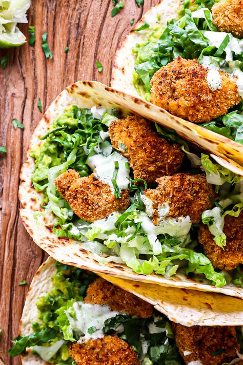 Crispy Cajun chicken bites, oven air-fried  served in warm tortillas with mashed lime avocado, crunchy lettuce with an addicting zesty garlick-y sauce.