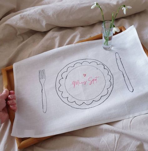 A personalised fabric placemat with a doodled place setting motif embroidered two ways onto a fresh white linen/cotton placemat. The knife, fork and plate place setting motif is freemotion stitched in black, creating a unique piece everytime as it's like drawing with a sewing maching.Your personalistation (up to 30 characters) is hand stitched in your choice of colour - please see the colour image and select from the drop down menuThere is an optional hand stitched heart motif available also in Swift Tattoo, Unique Placemats, Christmas Placemat, Dinner Places, March Hare, Like Drawing, Heart Motif, Christmas Placemats, Place Mats