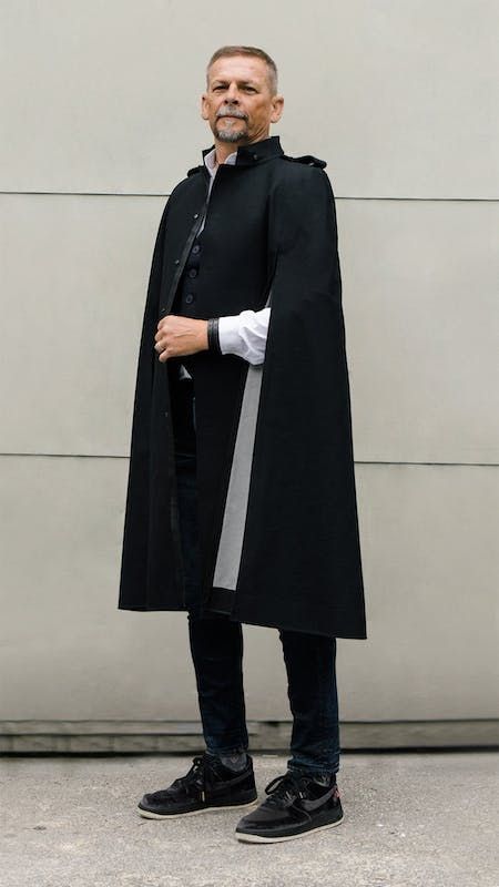 This men's style was designed to emphasize and endure for a look that’s as timeless as it is commanding. Featuring a simplistic silhouette, strong shoulders with epaulets, plus a collar inspired by a dress uniform, this element-resistant cloak-cape is a staple from day to night, season to season. Vegan leather trim detailing and clean cut lines elevate your look. Fit is designed to accommodate your style, from a classic suit to a wool sweater or puff jacket. | Cape De Coeur The Messenger - Black Cape Men, Mens Cape, Mens Poncho, Long Cape, Poncho Jacket, Puff Jacket, Strong Shoulders, Magic Aesthetic, Guys Clothing Styles