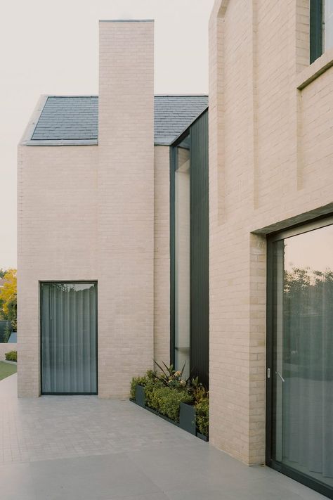 The gabled forms are clad in pale buff brick, with simple facades defined by vertical banding and contrasted by black metal window frames. 19 Century Art, Metal Window Frames, Structural Insulated Panels, 1920s House, Suburban House, Stone Barns, Brick Architecture, Exposed Concrete, Brickwork