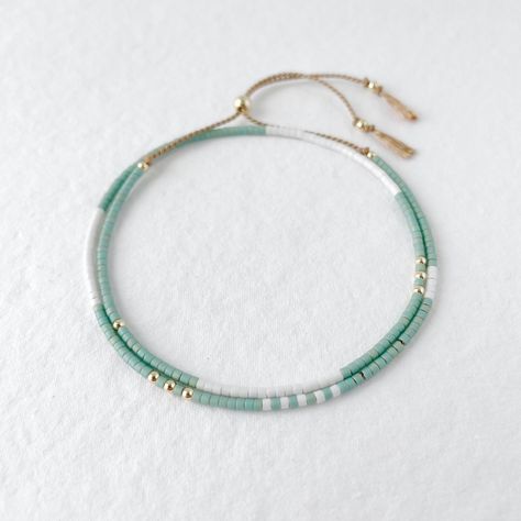 A beautiful dainty double wrap silk bracelet of matt aqua green and white glass beads and gold fill beads and sliding clasp to easily adjust to your size. Our Seaspray bracelet is inspired by the relaxing feeling of toes sinking into the soft sand while waves are crashing on the shore! The silk cord is beige and the beads are high quality Japanese Miyuki glass beads with a 14k gold filled sliding clasp and beads. Fits an average wrist size of up to 7 inches and tightens to 6.5in. Extends to fit String Friendship Bracelets, Bracelets Macrame, Bracelet Styles, White Beaded Necklaces, Silk Bracelet, Green Bracelet, Silk Cord, String Bracelet, Cord Bracelets