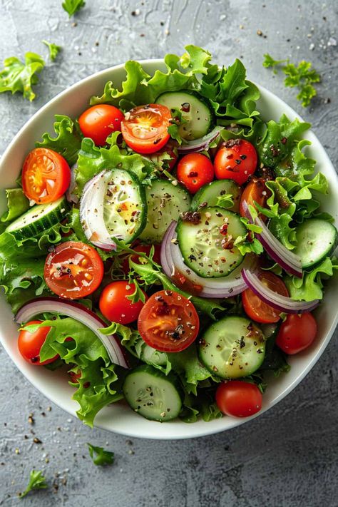 Overhead view of a colorful Mixed Greens Salad bowl filled with a variety of fresh lettuce, ripe cherry tomatoes, crisp cucumber slices, and slivers of red onion, all lightly coated with a zesty homemade dressing, showcasing a healthy and appetizing option. Garden Salad Recipe, Low Calorie Salad, Recipes On A Budget, Leafy Green Salads, Green Salad Recipes, Low Carb Salad, Healthy Food Dishes, Garden Salad, Idee Pasto Sano