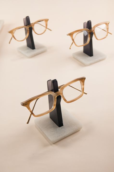 An understated glasses holder to store your spectacles. On your work desk in the office or your bedside table, this minimal Spectacles Holder is the perfect place to hang your eyeglasses. Constructed from recycled plastic bottles, the sturdy base-plate keeps your frame nice and high, away from dust and scratches. This semi-translucent edition is made from a transparent grey upright, with smoothly polished edges and a silky satin finish. Wooden Glasses Holder, Eyewear Store Design, Eyewear Display, Personalised Glasses, Furniture Details Design, Boutique Decor, Glasses Holder, Wood Accessories, Glass Holder