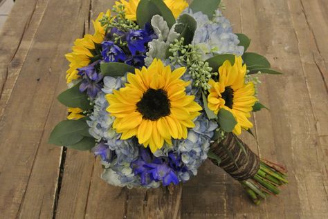 Blue and Yellow bridal bouquet with sunflowers,hydrangea,delphinium,seeded eucalyptus,dusty miller Sunflower Hydrangea Bouquet, Sunflowers And Hydrangeas Bouquet, Hydrangea And Sunflower Bouquet, Yellow Bridal Bouquet, Yellow Bridal Bouquets, Hydrangea Bouquet Wedding, Blue Flowers Bouquet, Bridal Bouquet Blue, Sunflower Wedding Bouquet