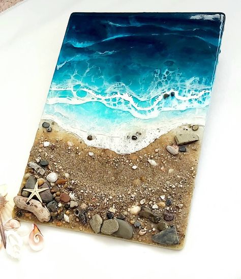 MADE TO ORDER - This particular piece is now sold but I can create something similar for you.  This beautiful seacape is individually handmade onto an mdf board using high quality epoxy resin mixed with different shades of blue capturing the tones of the sea.  Sand, shells and pebbles are added to create your own little beach, which I've collected whilst on my travels around the stunning Uk coastline and from my local beaches creating a perfect & tranquil moment captured for any beach lover. Perfect for placing onto an easel in your living room, hallway, family room just to mention a few. THE perfect eye-catching statement piece.  The shades of blue will be as close to the photos as I can get unless you specify a particular shade of blue, such as a brighter blue or a darker blue.  Also ple Ocean Themed Art, Beach Sand Art, Seashell Projects, Sea Colour, Sea Sand, Perfect Eyes, Beach Design, Beach Lover, Sand Art