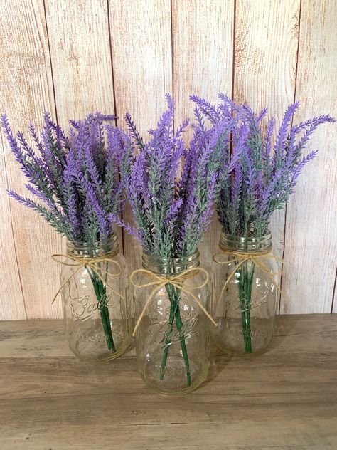 "These Lavender mason jars are perfect for wedding Centerpieces and bridal shower decor. These jars are also a great addition to your home decor, use as centerpieces or simple table decor.  Mason Jars are Quart Size Jars with twine attached at the top. Each jar has two purple faux lavender stems.  Lavender Bouquet is 14\" L Click my shop link below if you are interested in more styles of Mason Jars!  https://www.etsy.com/shop/TheCraftingJar" Rustic Table Decor Wedding, Purple Flower Centerpieces, Purple Table Settings, Simple Table Decor, Centerpiece Purple, Lavender Centerpieces, Lavender Wedding Theme, Purple Party Decorations, Farmhouse Wedding Decor