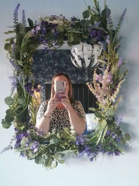 DIY mirror. I painted my Plain wood mirror dark blue then stapled artificial flowers to it to match the wall power on the opposite wall. Took about 1 hour to make and I think it really pulls the room together Mirror Decorated With Flowers, Diy Fairy Mirror Frame, Moss And Flower Mirror, Plant Mirror Frame, Dried Flower Mirror, Mirror With Plants Around It, Diy Mirror Frame Ideas Flowers, Mirror With Flowers Around It, Flower Theme Room