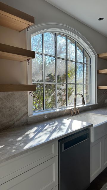 Andrew Roby on Instagram: "That natural light ☀️👌  As we bring the plans to life, we can’t help but pick out our favorite design elements in each renovation. This kitchen window is definitely one of our favorite features.   Design Architect: @charlotteinvironments . . . #kitchenrenovation #renovation #beforeandafterkitchen #openshelving #openshelvingkitchen #kitchenwindow #interiordesign #neutralkitchen #kitchendesign" Arch Window Kitchen Sink, Arched Opening Kitchen, Kitchen With Picture Window, Big Window In Kitchen, Large Window In Kitchen, Kitchen With Windows By Stove, Arched Kitchen Window, Windows Above Kitchen Sink, Window Sink Kitchen