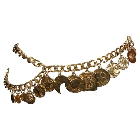 Very rare gilt charm belt designed by Yves Saint Laurent dating to the early 1990's. This fabulous belt features 16 coin charms suspended from a 37" linked chain from end to end which can be worn a few different ways including a necklace if you are creative. Charms include a heart, moon, star, clover, bird, fleur-de-lis, and large 'YSL' rectangular piece at center front. Belt as shown on a 24" waist. Very impressive belt. Good condition. Dope Jewelry Accessories, Earthy Style, Chain Belts, Belt Design, Belly Chain, Vintage Belts, Chain Belt, Girly Jewelry, Gianni Versace