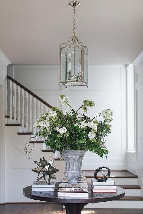 An arch lantern hangs over a styled round black wood entry table. Round Table Hallway, Round Entryway Table Styling, Entryway With Round Table, Round Entry Table Styling, Round Foyer Table Decor, Round Foyer, Foyer Table Decor, Round Foyer Table, Entrance Table Decor