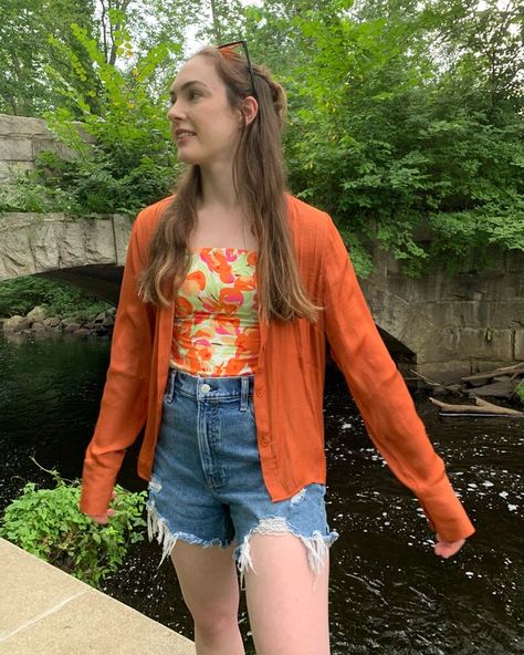 Sara is wearing an orange print top from shop cider with a long sleeve orange button up from glassons over it. She is also wearing a pair of high waisted mid wash jean shorts from abercrombie, orange sunglasses from shein, and white sneakers from forever21. She is outside. Season Transition Outfits, Shein Sunglasses, Summer To Fall Outfits, Shop Cider, Button Up Outfit, Aesthetic September, September Aesthetic, Transitional Outfits, First Day Of School Outfit