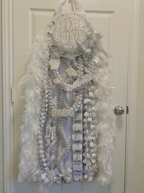 Senior white and silver heart shaped mega mum with white boa. Decorated with monogram and bear. morganmadegoods@gmail.com / morgan made on fb Senior really loved another mum and asked to make something very smiliar, they wanted to keep the same braids and structure. I used different ribbons and added perosnal touches. All White Senior Mum, White And Silver Senior Mum, Silver And White Mums, All White Homecoming Mum, White And Silver Homecoming Mum, Senior Year Mum, Hoco Mums Senior, Heart Shaped Homecoming Mums, Mum Ideas Homecoming Senior