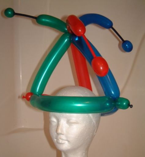 Try the HubPages Jester Hat!  Waaay back in the dawn of HubPages, the logo was three arrows intertwined, one each green, red and blue.  Hence, the inspiration. Balloon Twist Hat, Easy Balloon Animals, Balloon Hats, Balloon Figures, Balloon Hat, How To Make Balloon, Balloon Modelling, Jester Hat, Unicorn Balloon