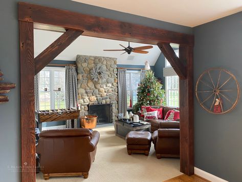 E. Braun reclaimed beams and boards were used to craft this eye-catching archway that makes a picture-perfect frame for the cozy living room and wonderful stone fireplace. www.braunfarmtables.com Accent Column Living Rooms, Wood Frame Room Divider, Rustic Archway Living Rooms, Framing An Archway, Archway To Living Room, Green And Stone Living Room, Wall Beams Living Room, Wood Archways In Homes, Rustic Beams In Living Room