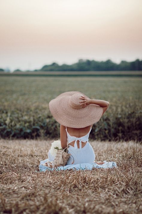 Annie B. sitting in field watching sunset in oversized straw hat and white linen jumpsuit taken from behind with bow Straw Hat Aesthetic, Oversized Sun Hat, White Linen Jumpsuit, Watching Sunset, Hat Aesthetic, Manga Hair, Oversized Hat, Wide Brim Straw Hat, Outdoor Pictures