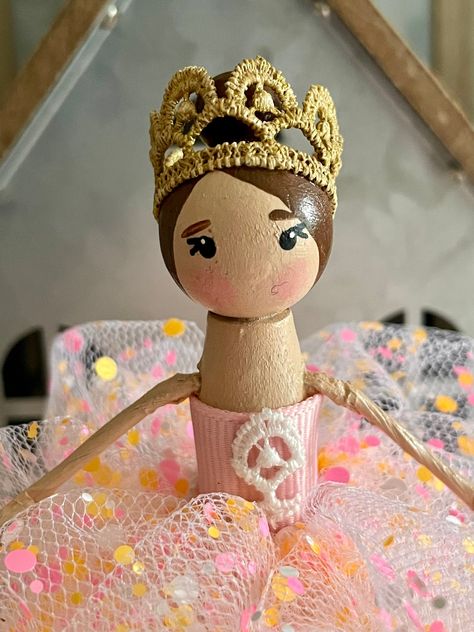 This sweet handmade Princess Ballerina clothespin figurine is dressed in a pink glittery polka dot tulle bubble dress with a pink satin top and wearing a gold crown on top of her head. She has brown hair in a bun on top of her head. She is made from a hand-painted wooden clothespin, a wooden bead head, and stands about 5 inches tall. This doll is a figurine but can be an ornament if wanted.  Things to keep in mind *This doll is for decorative purposes only and not intended as a toy. *Should not be handled by children under age 5 as small parts could come off and cause a choking hazard. *Product care: dust or wipe clean with a lightly damp cloth *Please keep in mind that each screen resolution is different so colors could vary slightly from image shown. Happy Shopping! Clothes Pin Ornaments, Diy Yarn Dolls, Pink Satin Top, Clothespin Doll, Princess Ballerina, Christmas Clothespins, Tutu Birthday, Doll Figurine, Wood Peg Dolls