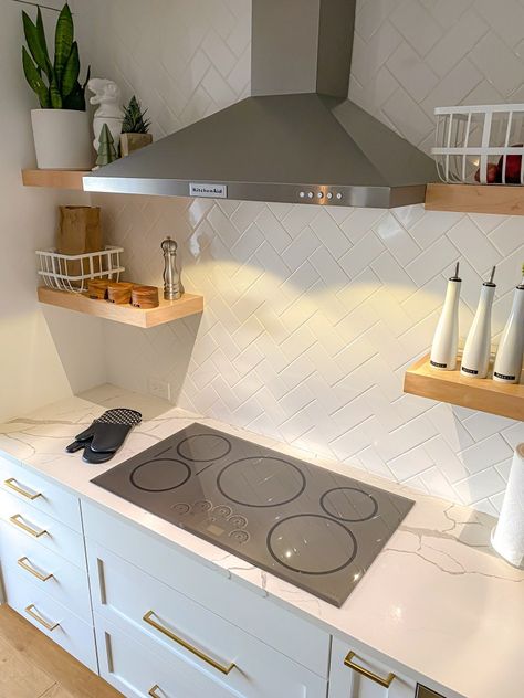 A kitchen with a grey induction cooktop, white cabinets, white tile, and brass pendant lights. Range Hood Over Induction Cooktop, Induction Cooktop Kitchen, Kitchen Cooktop, Myths And Facts, Induction Range, Induction Stove, Kitchen Hoods, Electric Cooktop, Common Myths