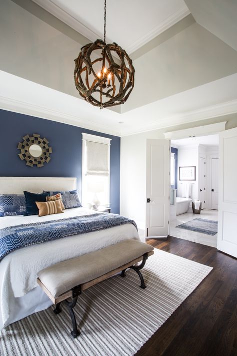 This master bedroom is part of a new construction project. It features a blue accent wall, custom bedding, hardwood floors, and french door leading into a spacious bathroom. Click the image to view more photos from this project! #bedroomdesign #blueaccent #interiordesign #furnishings #newconstruction #collectiondesignlifestyle Blue Master Bedrooms Decor, Blue Bedroom Walls, Blue Farmhouse, Blue Accent Walls, Bedrooms Decor, Master Room, Accent Wall Bedroom, Gray Bedroom, Master Bedrooms