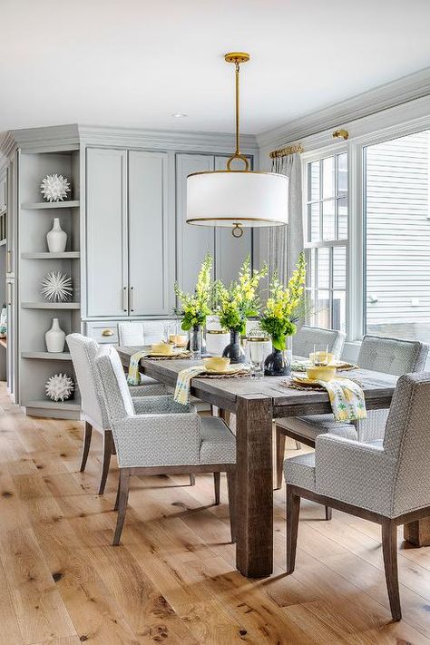 Gray pattern dining chairs surround a dark brown dining table lit by a white and gold hanging shade light. Dark Grey Dining Room, Dark Brown Dining Table, Dining Room Built Ins, Dining Room Built In, Dark Wood Dining Table, Dark Dining Room, Brown Dining Table, Transitional Dining Room, Dining Table Lighting