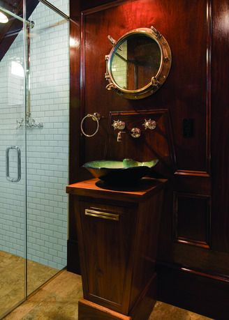 This new pool bath is fit  with the elegance of an old-time sailing vessel. The glossy wood paneling and oiled teak vanity exude warmth highlighted by period-style lighting. The blue green glass ve… Captains Quarters Decor, Nautical Room Ideas, Nautical Interior Design, Captain's Quarters, Captains Quarters, Nautical Interior, Teak Vanity, Bathroom Cabinets Designs, Pool Bath