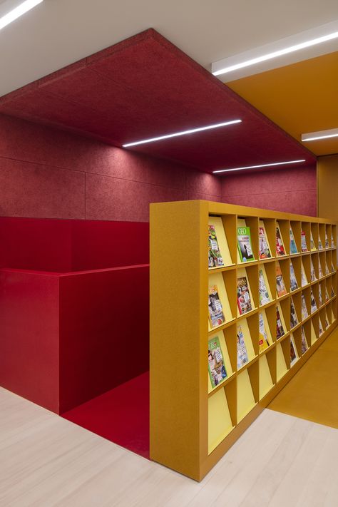 This library has been transformed into a kind of communal reading space, where visitors like to come and spend time as if they were in a large living room. Troldtekt acoustic panels in a special shade of red have also been integrated to create a calm environment. #goodacoustics #holzwolleplatten #träullsplattor #troldtekt | Architects: Hansen Architekt, Freiburg Creative Library Design, Colourful Library, Bauhaus Office, Exposed Concrete Facade, Acoustics Design, Calm Environment, External Staircase, Reading Space, House Dressing