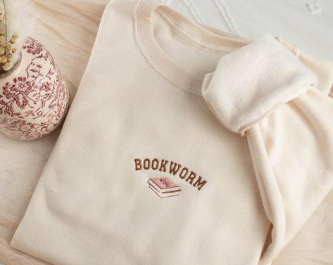 Embroidered Bookworm Sweatshirt Stay cozy and fun with our uniquely embroidered sweatshirt! Made with love and THOUSANDS of threads! -Unisex Size (Please see the size chart for more details that can be found in the photos section)  We recommend comparing your favorite sweatshirt to our size chart to find the best size for you! Unisex Crewneck -50% cotton 50% polyester -Super soft -Pre-shrunk -Unisex -Design size is 3''-4"  Thread: We use the best quality threads for our embroidery designs. Aesthetic Embroidered Sweatshirt, Bookish Embroidery, Book Sweatshirts, Bookworm Sweatshirt, Sweatshirts Embroidery, Etsy Sweatshirts, Sweatshirts Aesthetic, Embroidered Book, Bookworm Gifts