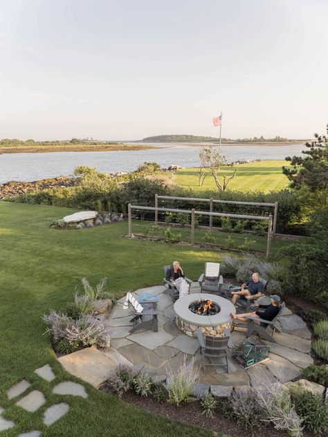 A paver pathway imprinted into this pristine seaside lawn leads to a spacious stone slab patio and fire pit. Ringed with native plants and granite boulders, the outdoor entertainment space features plenty of room for family and friends to pull up a weathered Adirondack chair for s'mores by the sea. In the background, vegetable gardens taper off into the soothing ocean views.