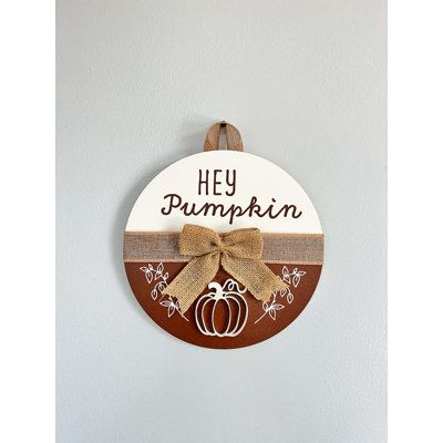 Our line of seasonal door hangers are the perfect touch of farmhouse and rustic décor. Embellished with a 1-1/2” wide natural burlap ribbon across the center with a matching bow, this sign is UV printed with a charming design. It can be hung on a door or wall with the matching burlap ribbon hanger. The pumpkin is a wood cutout attached to give a 3D effect to the design. This decorative door sign is are available in both 10” and 14” diameters. They are a great way to welcome your family, friends Wood Circle Door Hanger Christmas, Winter Wooden Door Hangers, Seasonal Door Hangers, Hey Pumpkin, Wooden Door Signs, Fall Stuff, Fall Door Hangers, Family Fun Night, Wood Door Hangers