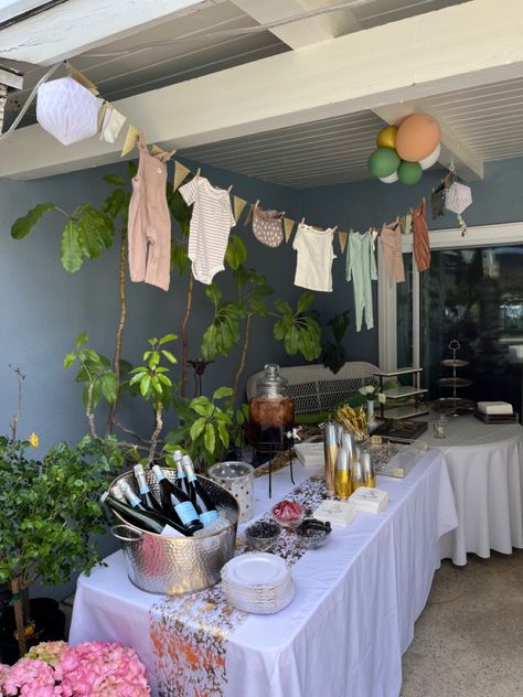 Clothes line with baby clothes and glitter triangles hanging over a dessert table. Onesie Clothes Line Shower Ideas, Baby Clothes Line Decor, Clothes Line Baby Shower Decoration, Clothesline Baby Shower Decor, Baby Shower Clothes Line, Shrek Baby, Neutral Baby Shower Decor, Baby Shower Clothesline, Baby Shower Clothes